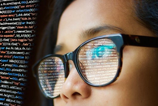 Frau mit Spiegelung von Sourcecode in der Brille